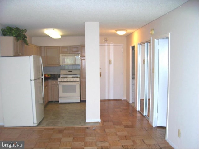 kitchen with white appliances, light brown cabinetry, and a textured ceiling