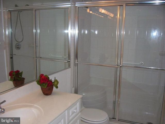 bathroom with vanity, a shower with door, and toilet