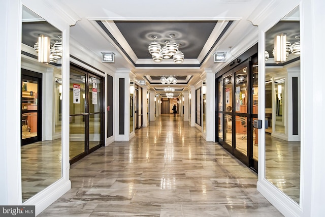 interior space featuring a raised ceiling, crown molding, french doors, and a chandelier