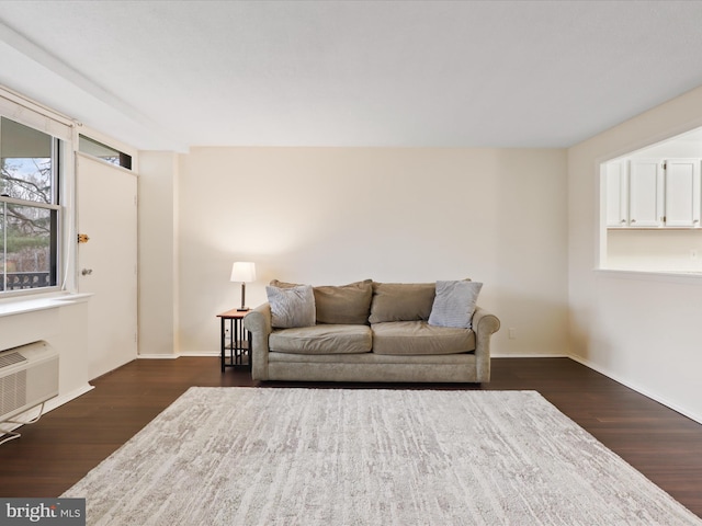 living room with dark wood-type flooring and an AC wall unit