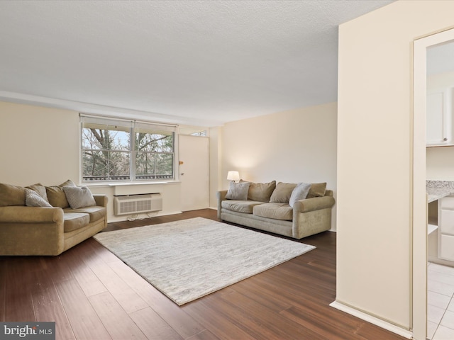 living room featuring hardwood / wood-style flooring, a wall mounted air conditioner, and a textured ceiling