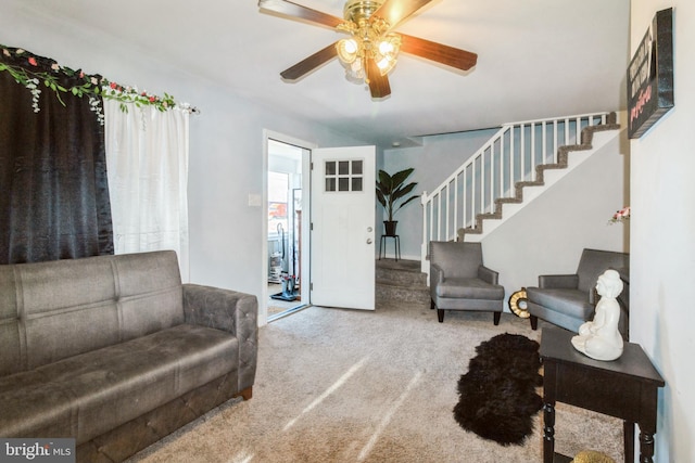 carpeted living room featuring ceiling fan and stairs