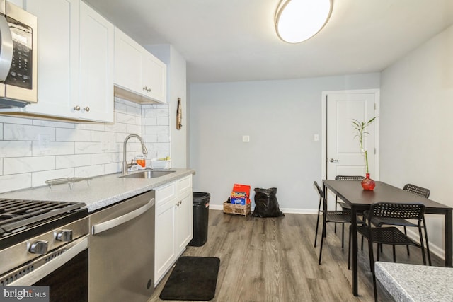 kitchen with tasteful backsplash, white cabinets, stainless steel appliances, light countertops, and a sink