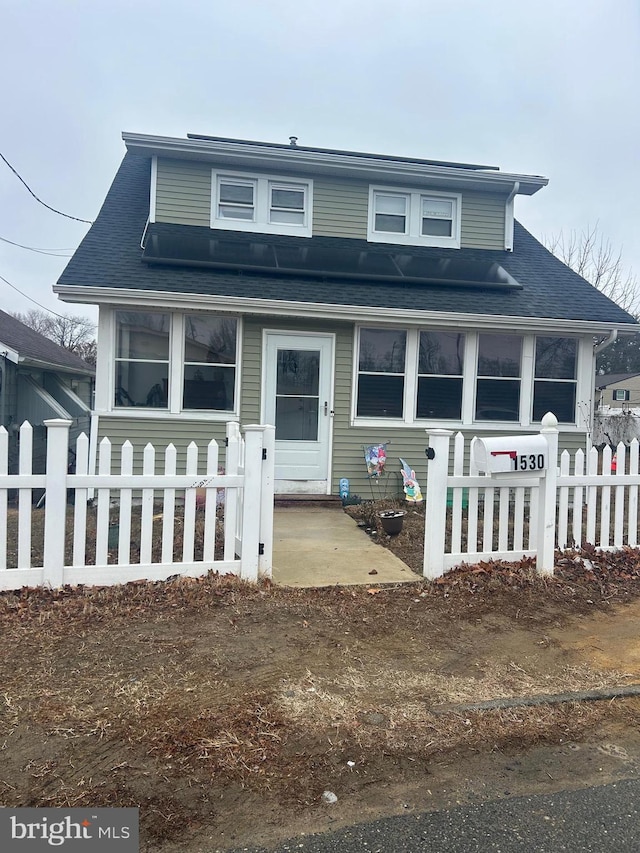 bungalow-style home featuring a patio, a shingled roof, and a fenced front yard