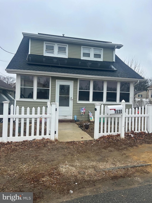 bungalow-style house with a fenced front yard and a shingled roof