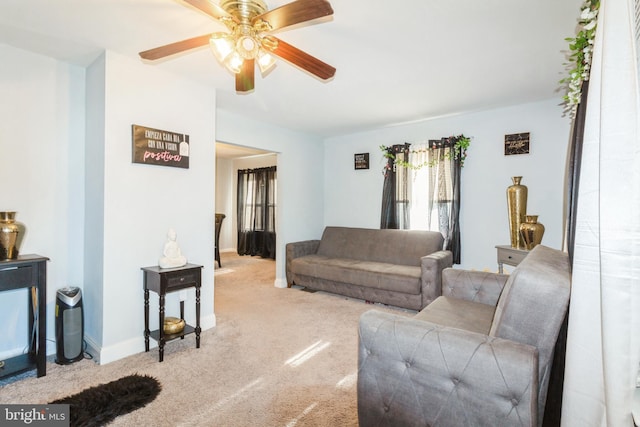 living area featuring a ceiling fan, light carpet, and baseboards