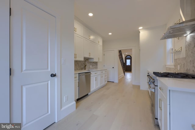 kitchen featuring tasteful backsplash, stainless steel appliances, white cabinets, and island exhaust hood