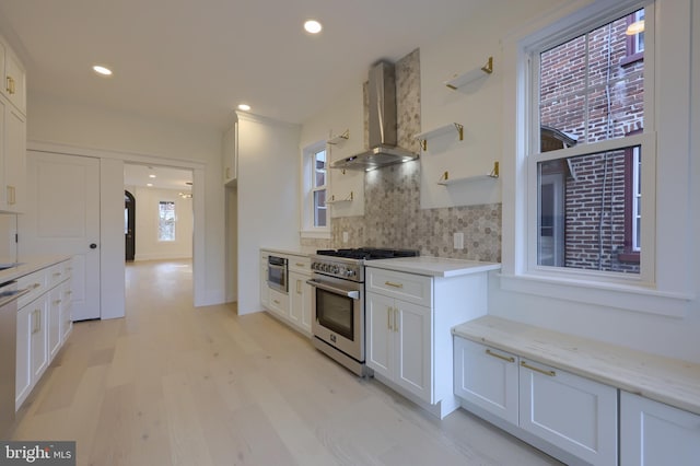 kitchen with white cabinets, wall chimney exhaust hood, and appliances with stainless steel finishes