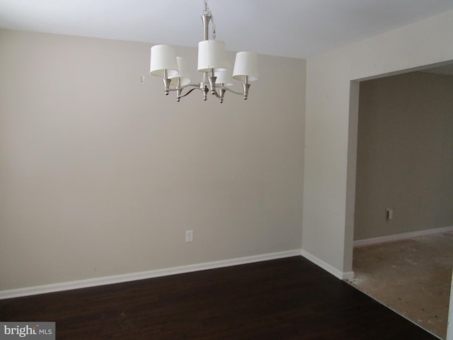 spare room featuring a notable chandelier and dark hardwood / wood-style flooring