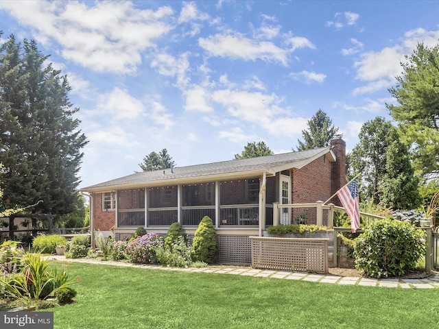 back of property with a sunroom and a yard