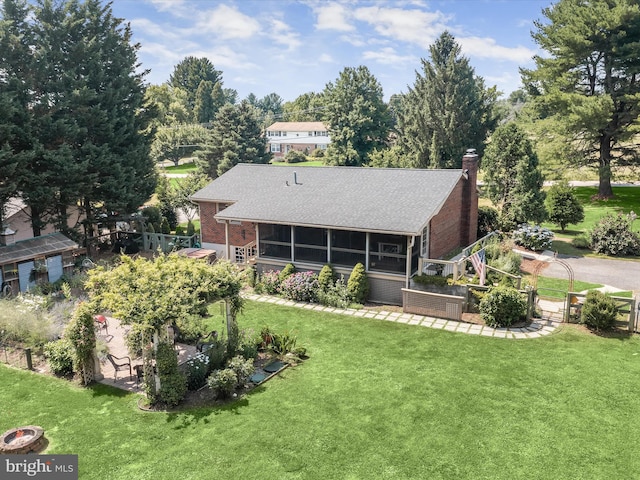 rear view of property with a sunroom and a lawn