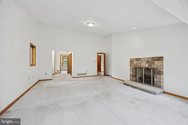 unfurnished living room featuring baseboards, light colored carpet, and a fireplace with raised hearth