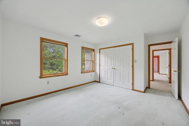 unfurnished bedroom with light colored carpet, a closet, and baseboards