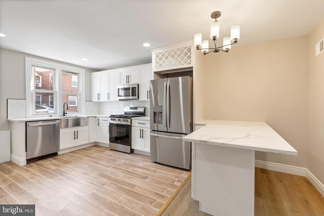 kitchen with hanging light fixtures, kitchen peninsula, white cabinets, and appliances with stainless steel finishes