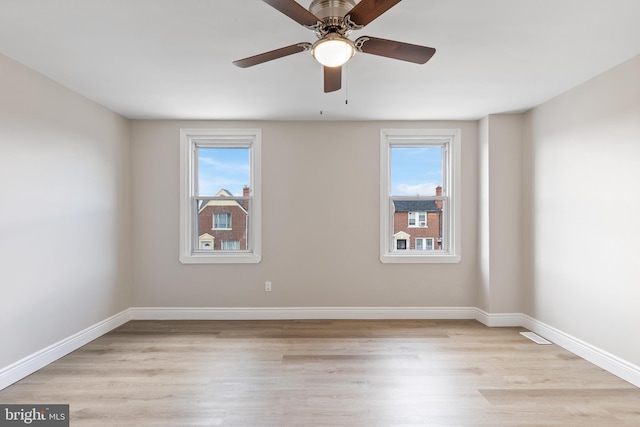 unfurnished room featuring ceiling fan, a wealth of natural light, and light wood-type flooring