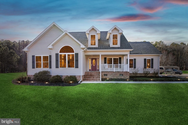 cape cod house with a porch and a yard