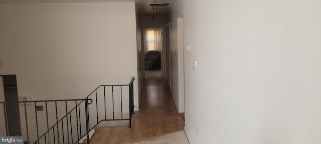 corridor with visible vents, an upstairs landing, and wood finished floors