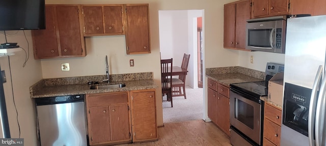 kitchen featuring appliances with stainless steel finishes, brown cabinets, and a sink