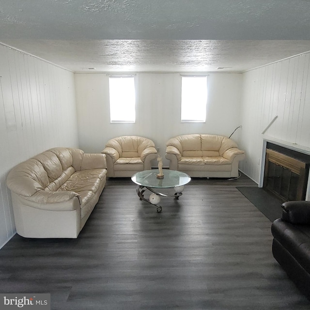 living room featuring a glass covered fireplace, wood walls, a textured ceiling, and wood finished floors