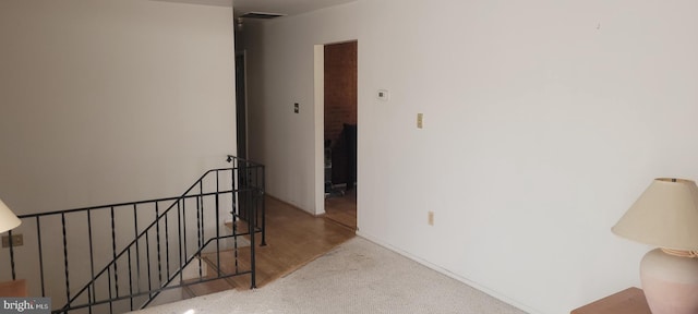 hallway featuring baseboards, visible vents, and an upstairs landing