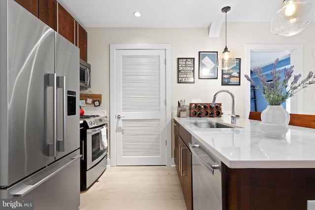 kitchen featuring sink, dark brown cabinets, stainless steel appliances, an island with sink, and decorative light fixtures