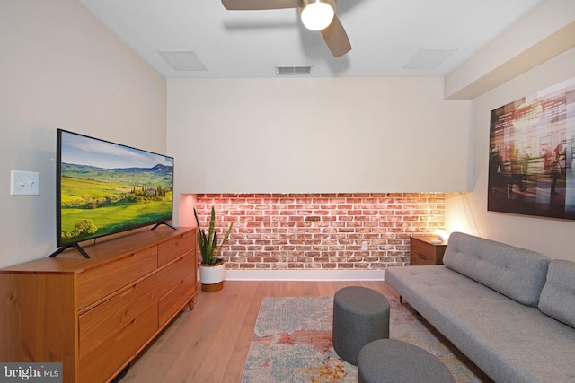 living room with ceiling fan, brick wall, and light hardwood / wood-style floors