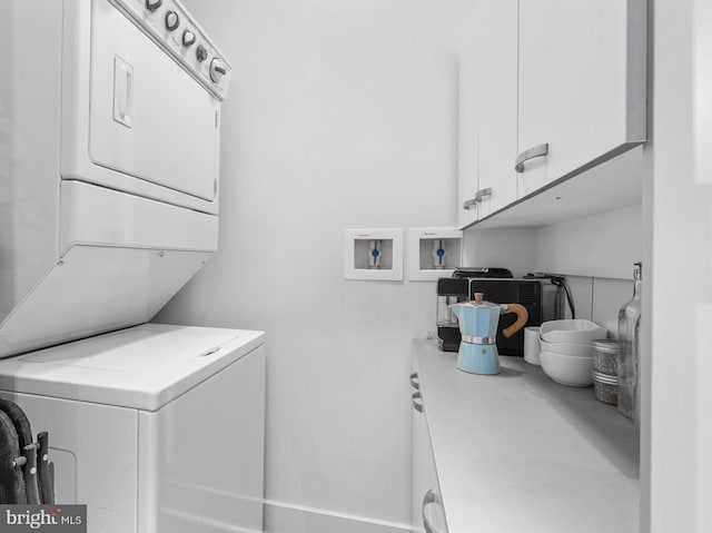 washroom featuring cabinets and stacked washing maching and dryer