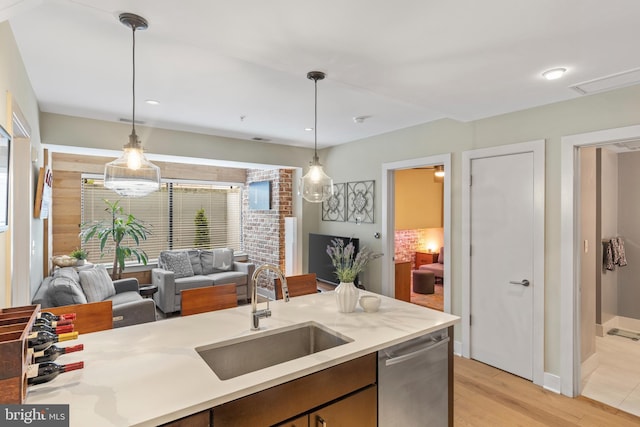 kitchen featuring pendant lighting, stainless steel dishwasher, light hardwood / wood-style floors, and sink