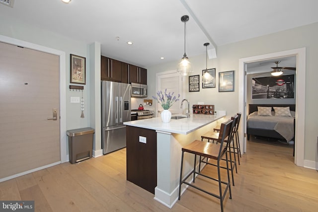 kitchen with sink, hanging light fixtures, stainless steel appliances, a kitchen bar, and kitchen peninsula