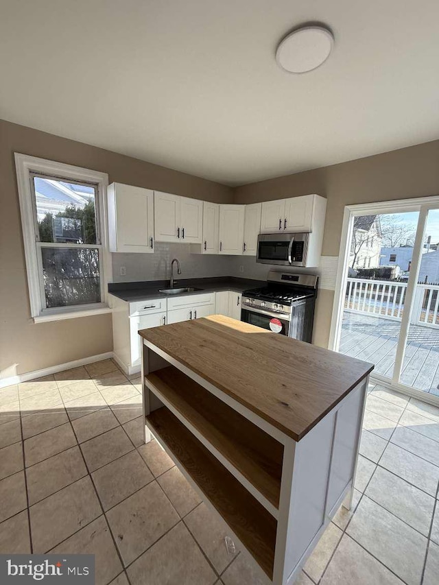 kitchen with white cabinetry, sink, light tile patterned flooring, and appliances with stainless steel finishes