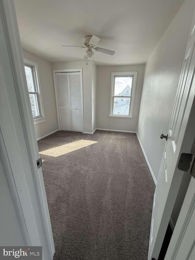 unfurnished bedroom with carpet floors, ceiling fan, and a closet