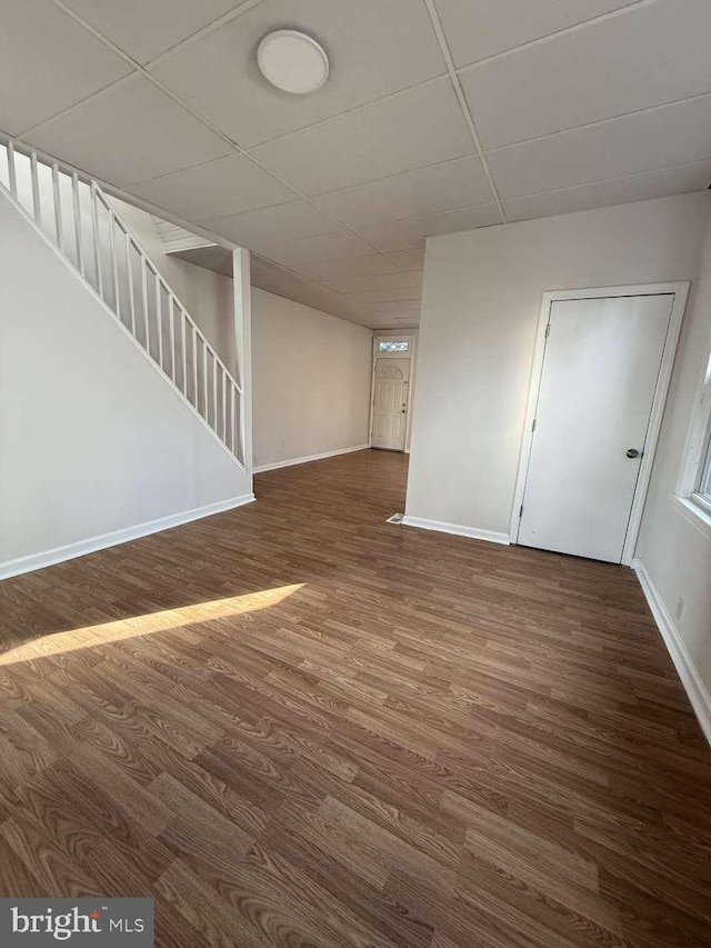 basement with dark hardwood / wood-style flooring and a paneled ceiling