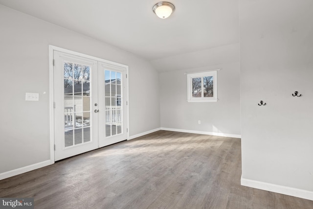 spare room with vaulted ceiling, french doors, baseboards, and wood finished floors