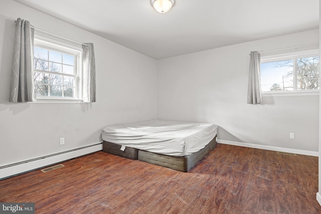 bedroom with wood finished floors, visible vents, and baseboards