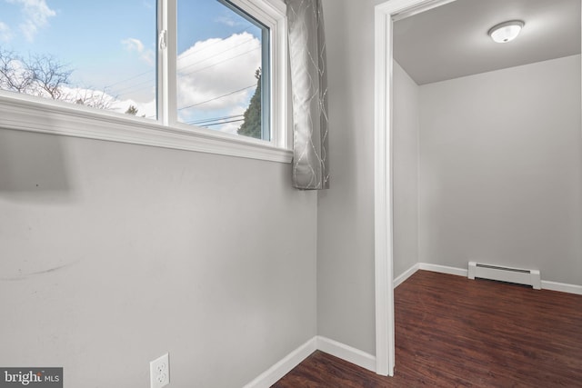 interior space featuring baseboards, baseboard heating, and wood finished floors