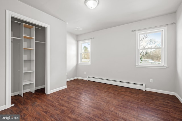 unfurnished bedroom with wood finished floors, baseboards, and a baseboard radiator