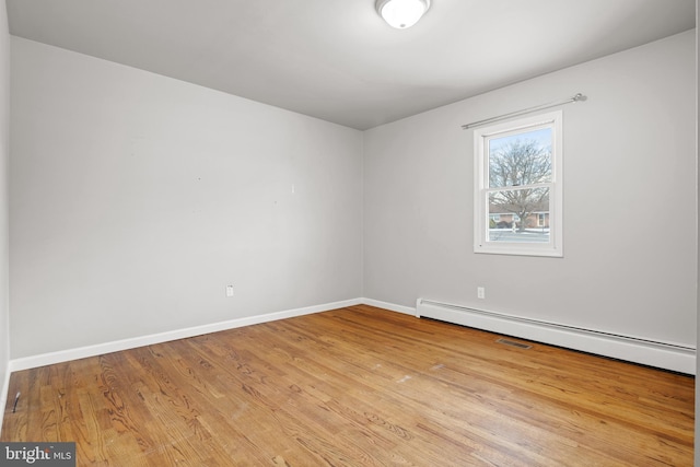 unfurnished room with baseboards, baseboard heating, and wood finished floors