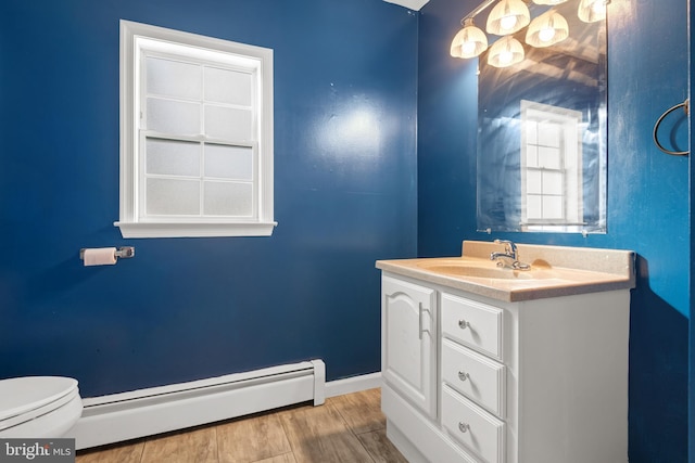 half bathroom featuring vanity, wood finished floors, baseboards, toilet, and baseboard heating