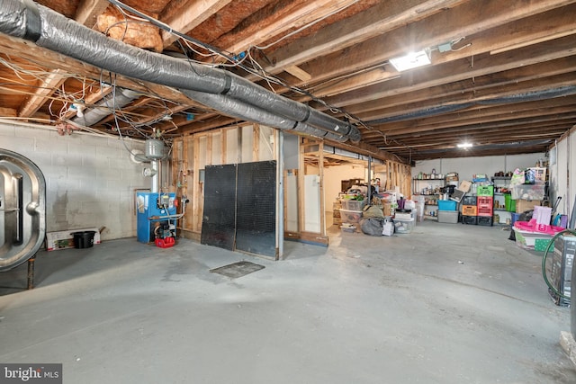 unfinished basement with concrete block wall and a heating unit