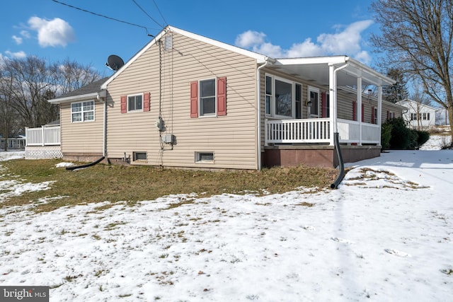 snow covered property with covered porch