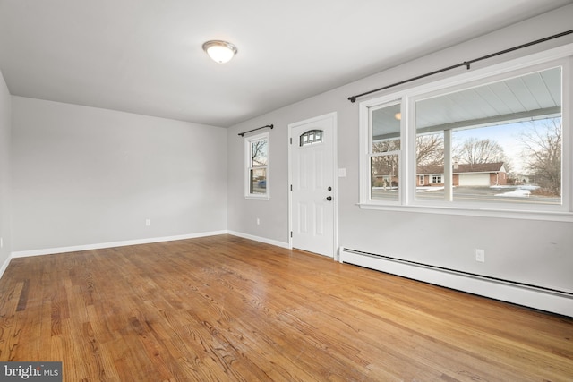 spare room with a baseboard heating unit, baseboards, and wood finished floors