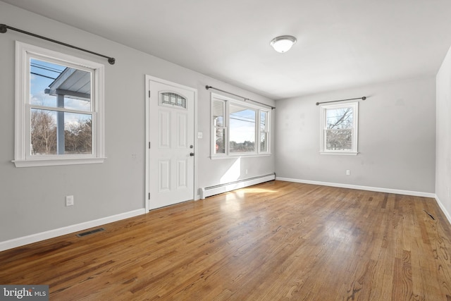 entryway with a baseboard heating unit, baseboards, visible vents, and wood finished floors