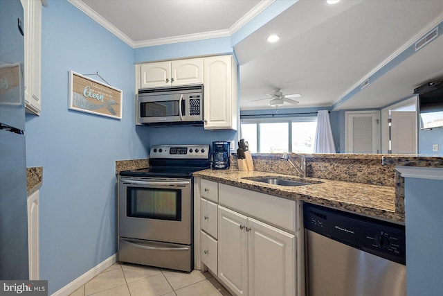 kitchen with sink, crown molding, light tile patterned floors, appliances with stainless steel finishes, and white cabinetry