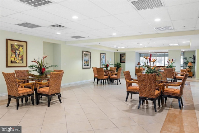 dining area with a paneled ceiling and light tile patterned floors