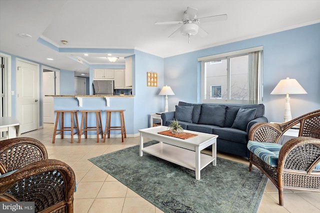 tiled living room featuring ceiling fan, ornamental molding, and a tray ceiling