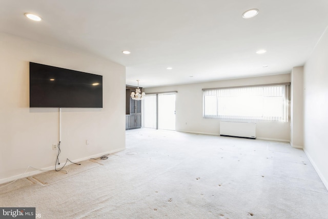 unfurnished living room with light colored carpet and a chandelier