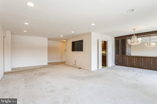 carpeted spare room with an inviting chandelier