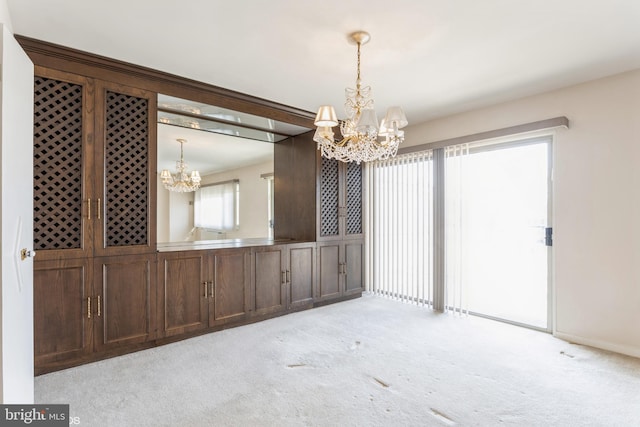 carpeted empty room with an inviting chandelier