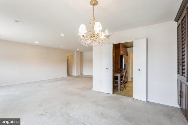 carpeted empty room with an inviting chandelier