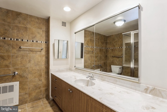 bathroom featuring a tile shower, heating unit, vanity, toilet, and tile patterned floors